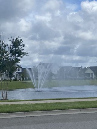 A scenic pond with a fountain and nearby homes in Seven Pines 50' Rear Entry by David Weekley Homes (Jacksonville, FL).