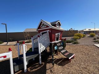Community Amenities Charming playground with a whimsical playhouse in Zanjero Pass by D.R. Horton (Waddell, AZ).