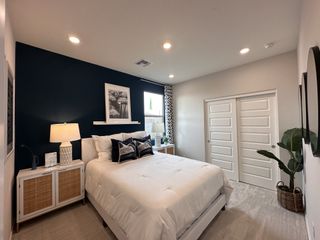 Model Home A cozy bedroom with a bold navy accent wall, plush bedding, and chic decor. Features sleek double-door closets.