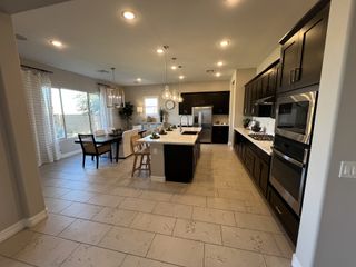 A modern kitchen with dark cabinetry, stainless steel appliances, and a cozy dining area filled with natural light.