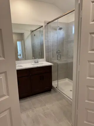 A modern bathroom featuring a glass shower, elegant vanity, and neutral tile flooring for a sleek, clean look.