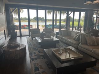 A luxurious living room with modern decor, overlooking a scenic lake and outdoor seating area, perfect for relaxation.