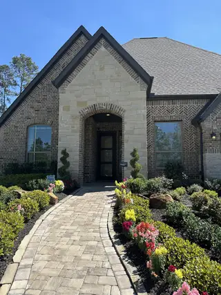 A charming brick home with landscaped path in Evergreen by Chesmar Homes (Conroe, TX).