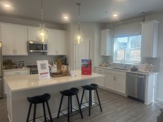 A modern kitchen with sleek white cabinetry, pendant lighting, and an inviting island with stool seating.