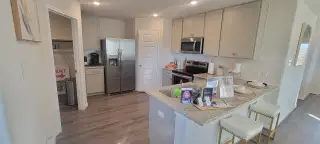 A modern kitchen featuring stainless appliances, light cabinetry, and an inviting island with barstool seating.