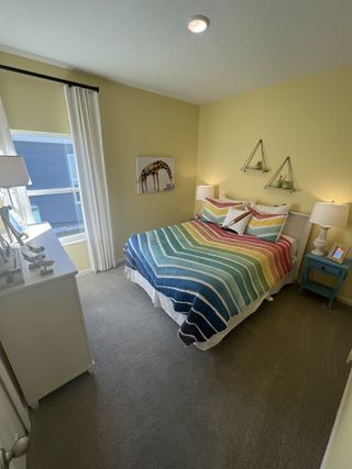 A cozy bedroom with a colorful striped bedspread, whimsical art, and soft lighting, creating a cheerful ambiance.