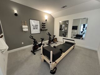 A modern home gym with exercise bikes, a Pilates reformer, motivational decor, and large mirrors.
