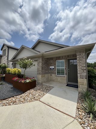 A charming brick home with vibrant flower beds in Prairie Lakes by D.R. Horton (Buda, TX).