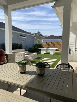 A charming covered patio with a dining area, potted greenery, and a stylish outdoor kitchen perfect for entertaining.