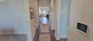 Model Home A welcoming hallway with archways, modern lighting, and an open layout leading to a bright living space.