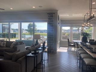 A sunlit living and dining space with lake views, cozy seating, stylish decor, and large windows.