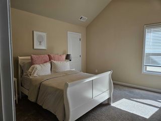 A cozy bedroom with a sloped ceiling, white sleigh bed, and soft pink accents for a serene atmosphere.
