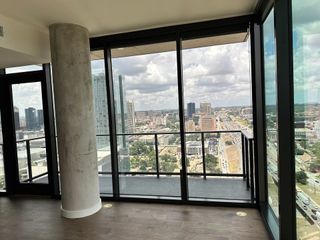 A modern high-rise room with floor-to-ceiling windows offering stunning city views and a sleek concrete pillar.