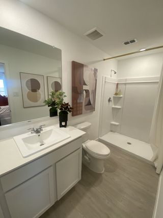 A modern bathroom with abstract art, white vanity, a sleek shower, and stylish decor.