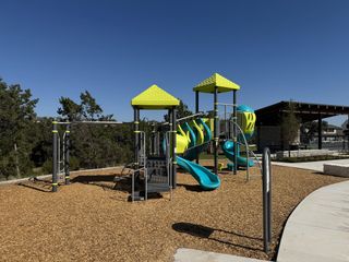 A vibrant playground with slides and a pavilion in Parkside on the River by Coventry Homes (Georgetown, TX).