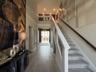An elegant hallway with modern decor, textured wall art, and a sleek staircase leading to a bright living area.