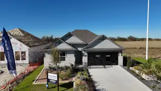 Charming gray home with a manicured lawn and driveway in Eastern Wells by D.R. Horton (Jarrell, TX).