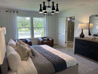 A cozy bedroom featuring a plush bed, chic seating area, and modern ensuite bathroom with contemporary fixtures.