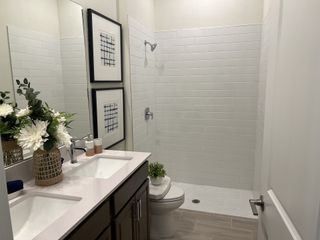 A chic bathroom featuring a twin sink vanity, white subway tiles, and elegant decor with framed art and fresh flowers.
