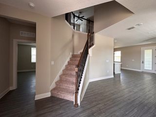 Model Home An elegant interior featuring a carpeted staircase, sleek wood flooring, and neutral-toned walls with abundant natural light.