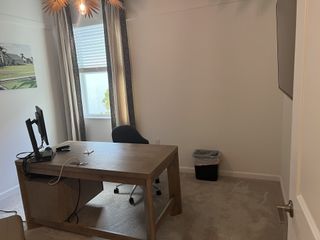 A minimalistic home office with a wooden desk, modern chair, and natural light filtering through elegant curtains.