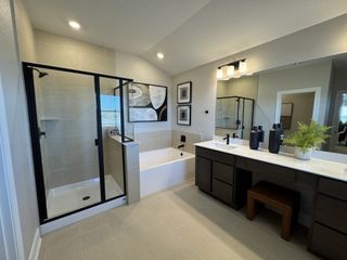 A modern bathroom featuring a sleek shower, a tub, dark wood vanity, and stylish lighting.