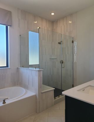 A modern bathroom featuring a glass-enclosed shower, stylish tiling, and a sleek bathtub for a relaxing ambiance.