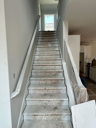 A staircase in a home under construction, featuring light gray walls and a modest design.