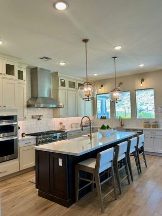 A spacious kitchen featuring a large island, sleek stainless steel appliances, and pendant lighting.