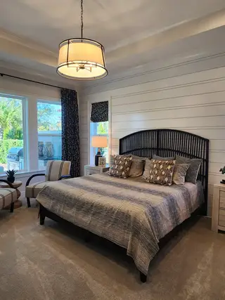 Model Home A bright, serene bedroom featuring a cozy bed, lounge chairs, and ample natural light.