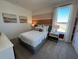 A cozy bedroom with modern art, a plush bed, and natural light streaming through a large window with scenic views.