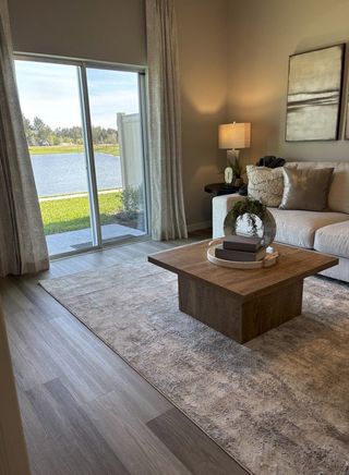 Cozy living room with plush sofa, modern table, and serene lake view through large sliding doors.