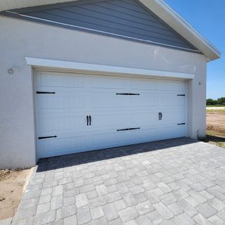 A modern white garage with elegant accents and a paved driveway in Yucatan Gardens by CFB Homes (Azalea Park, FL).
