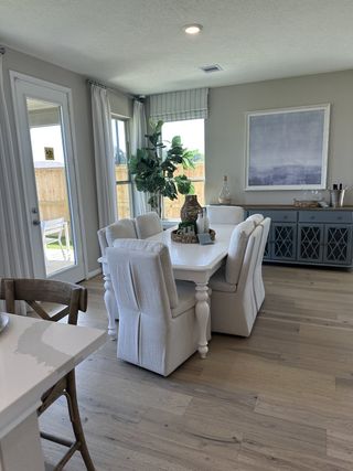 A cozy dining area with soft upholstered chairs, a white table, and a large window for natural light.