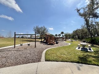 A scenic playground with swings, slides, and picnic tables, perfect for family fun in Kindred by D.R. Horton (Kissimmee, FL).