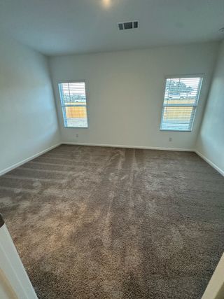 A cozy bedroom featuring soft carpet and bright windows, creating a welcoming and comfortable atmosphere.