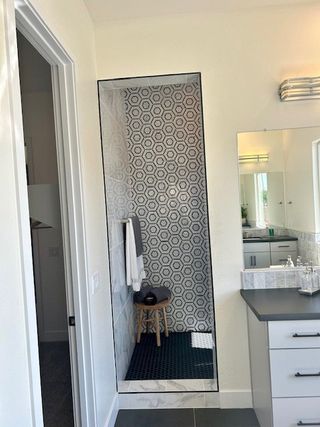A modern bathroom featuring geometric tile shower, sleek vanity, and elegant lighting.