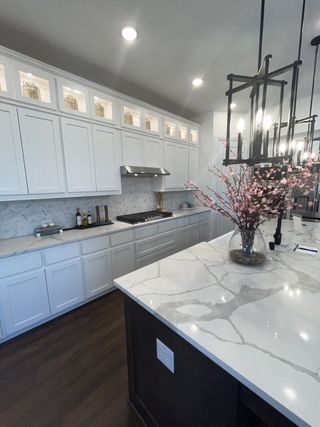 A gourmet kitchen with marble countertops, sleek cabinetry, and modern lighting in The Parks at Wilson Creek by Highland Homes (Celina, TX).