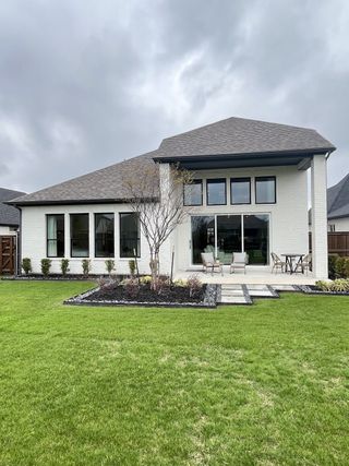 Street view A modern white brick home with a lush yard in Devonshire by Shaddock Homes (Forney, TX).