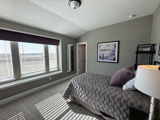 A cozy bedroom with a large window, soft gray tones, textured bedding, and modern artwork for a serene atmosphere.