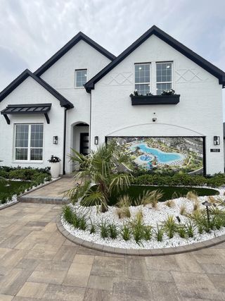 Street view A stunning white brick home with lush landscaping in Santorini by Megatel Homes (Seagoville, TX).