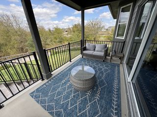 Model Home A cozy balcony with stylish outdoor furniture, a patterned rug, and scenic views of greenery.