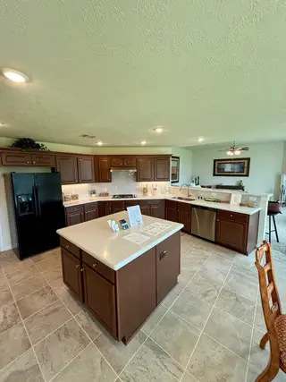 Spacious kitchen with rich wood cabinets, sleek black appliances, and a central island for meal prep and gathering.