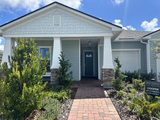 A charming Craftsman-style home with lush landscaping in Reverie at Palm Coast by Dream Finders Homes (Palm Coast, FL).