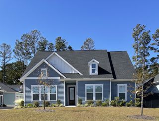 Charming blue home with white accents and manicured lawn in Point Hope by Pulte Homes (Charleston, SC).