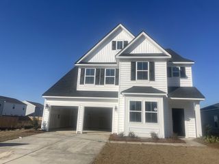 A bright, modern two-story home in Lindera Preserve at Cane Bay Plantation (Summerville, SC) by Lennar, features a white exterior and a two-car garage.