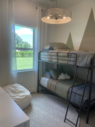 Model Home A cozy kids’ room featuring bunk beds, a plush beanbag, and soft lighting, perfect for relaxation and play.