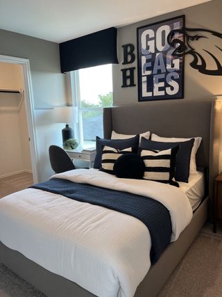 A stylish bedroom with a gray upholstered bed, sports-themed decor, and a cozy ambiance.