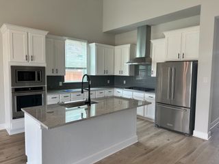 A modern kitchen featuring white cabinetry, stainless steel appliances, and a sleek island with granite countertops.