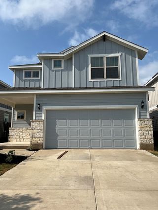 A charming blue-gray home with stone accents and a spacious driveway in Santa Rita Ranch by Pulte Homes (Liberty Hill, TX).
